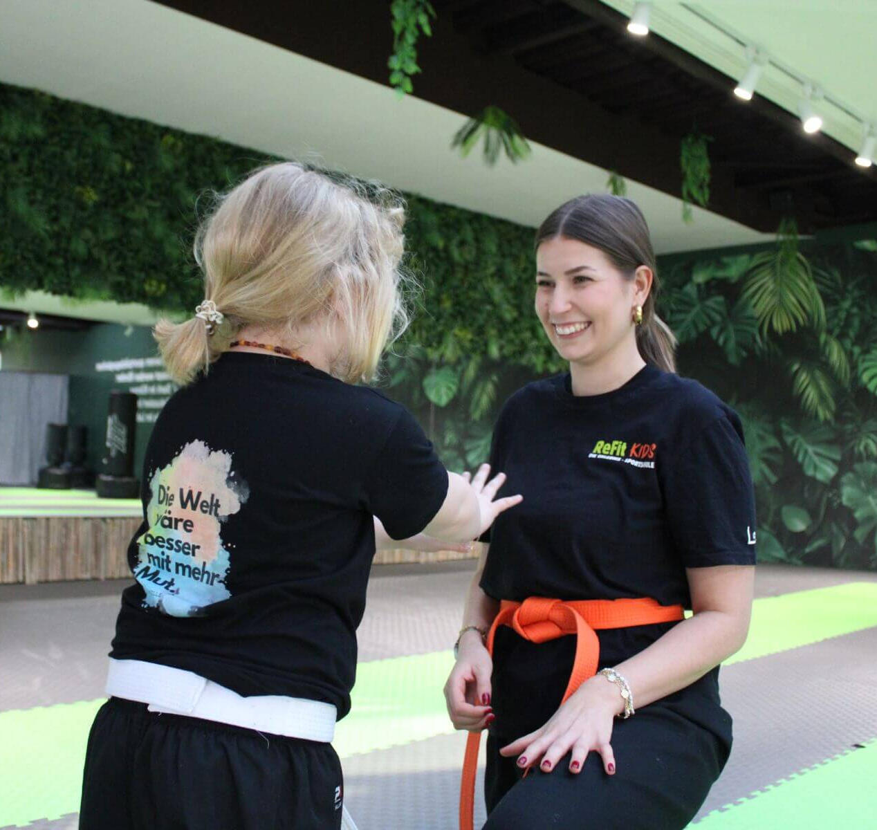 ReFit Kids Coach kniet vor einem Kind im Training — persönliche Betreuung auf Augenhöhe